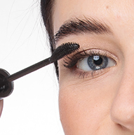 Una donna applica il mascara con un pennello, aggiungendo volume alle sue ciglia e perfezionando il suo trucco occhi.
