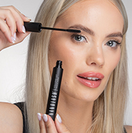 Una donna applica con attenzione il mascara alle sue ciglia, tenendo il pennello vicino per una finitura perfetta.