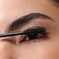 Un'immagine ravvicinata di una persona che applica il mascara nero Nanolash alle sue ciglia superiori usando un applicatore.