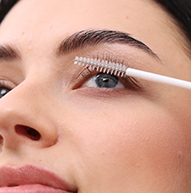 Una donna usa un pennello per applicare il mascara, migliorando meticolosamente le sue ciglia per un aspetto raffinato e sofisticato.